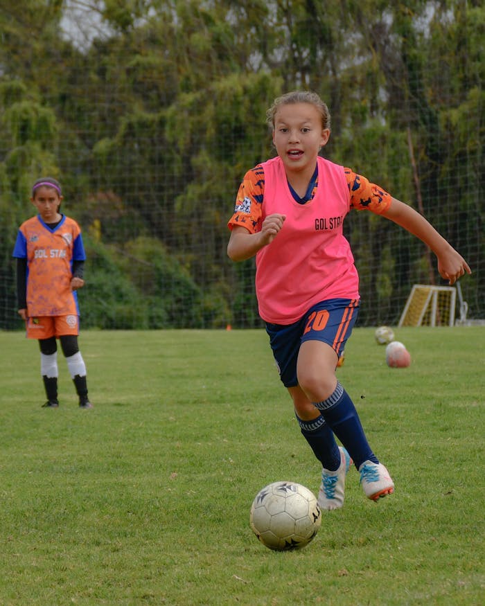 Energetic young girls engaged in a soccer match on a grassy field, showcasing teamwork and athleticism.