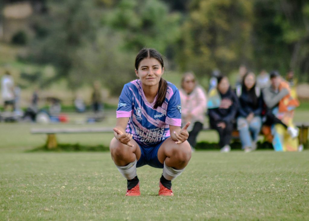 Young female soccer player crouching on an outdoor field.